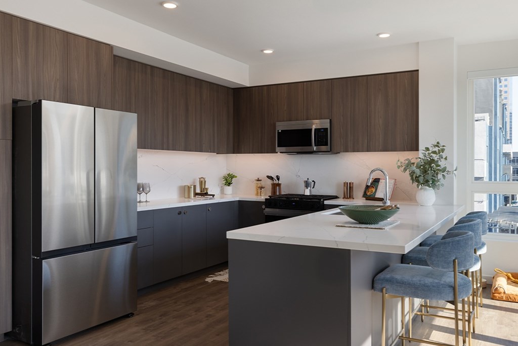 A modern kitchen with a stainless steel refrigerator and a white countertop.