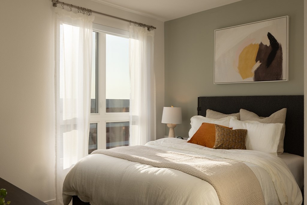 A bedroom with a large bed and a painting on the wall.