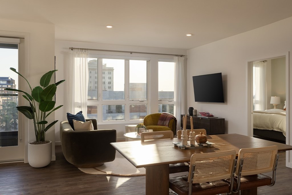 A modern living room with a brown sofa, a wooden table, and a flat-screen TV mounted on the wall.