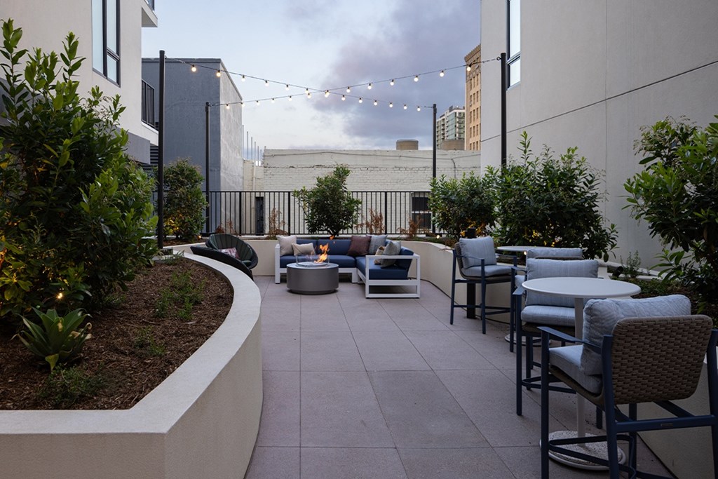 A patio with chairs and a table with a fire pit in the middle.