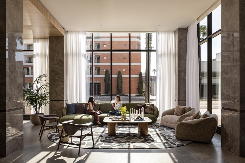 A modern living room with a large window and a view of a building outside.