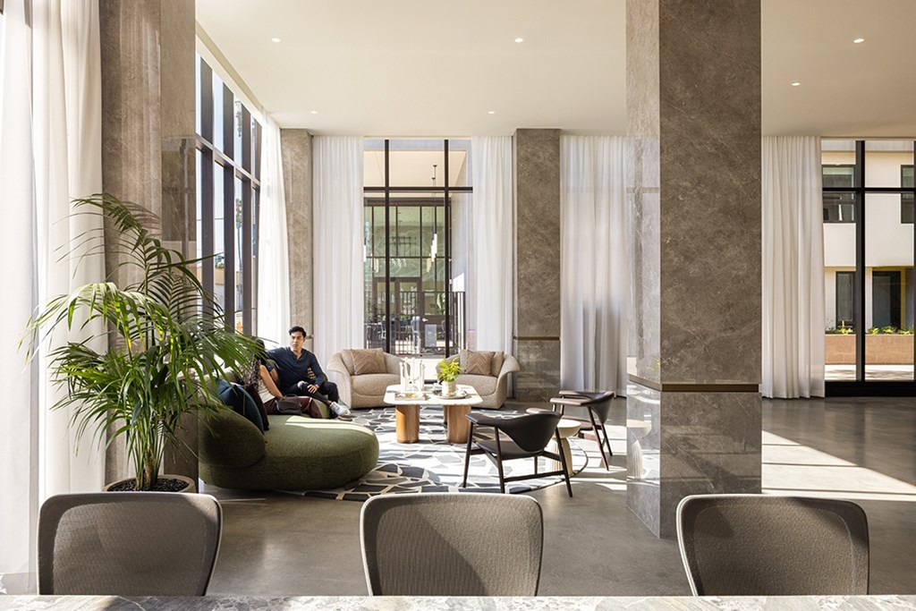 A man is sitting on a couch in a room with a large window.