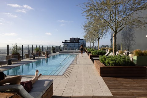 A man is sunbathing by a pool on a sunny day.