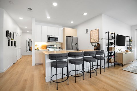 A kitchen with a white counter and bar stools.
