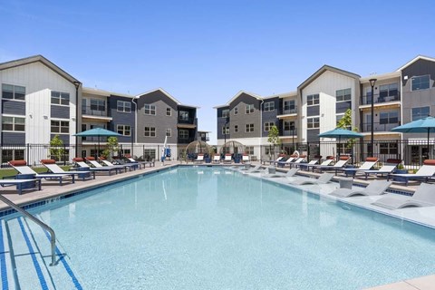 A large swimming pool in front of apartment buildings.