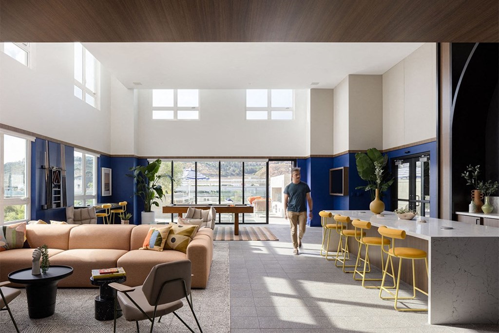 a man walks through a large living room with blue walls and white ceilings