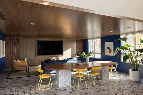 a large table with yellow chairs in a room with blue walls and a large tv on the