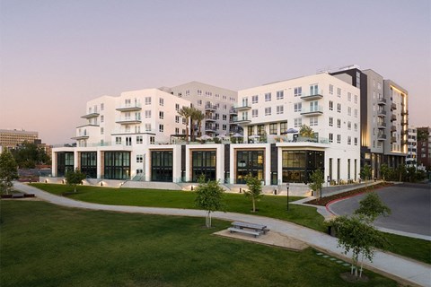 a rendering of a white building with many windows and a grassy area in front of it