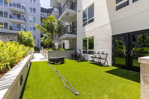 a yard with grass and lawn equipment in front of an apartment building