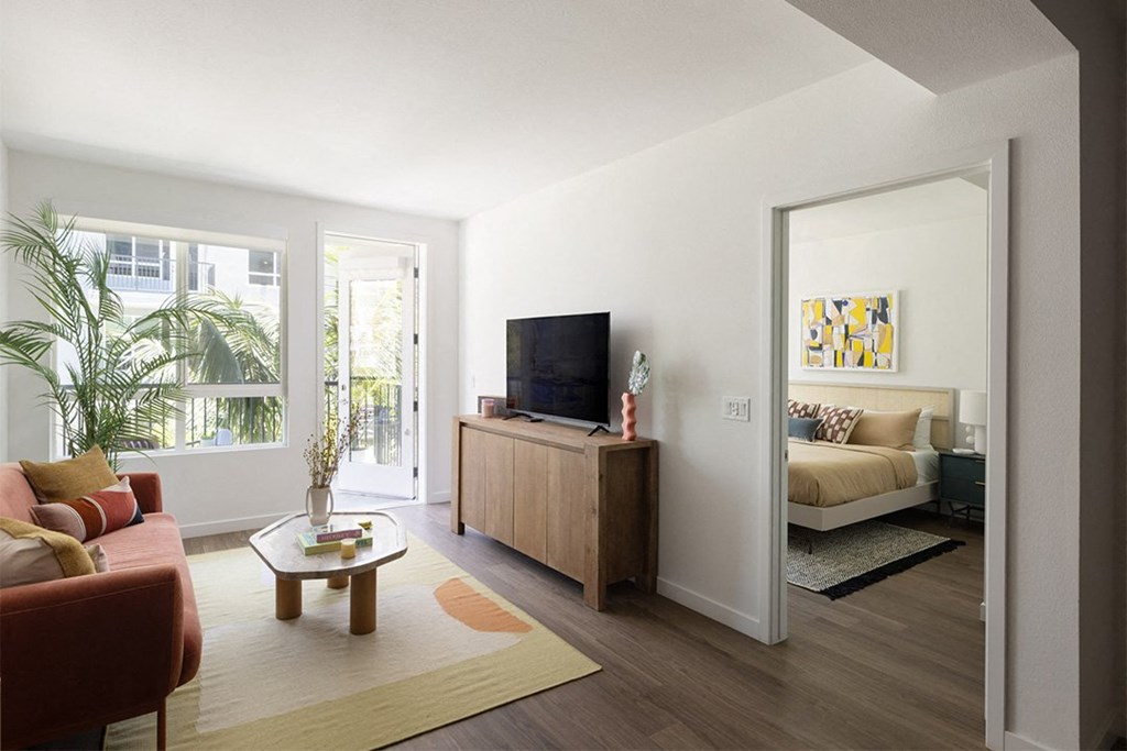 a living room with a tv and a bedroom in the background