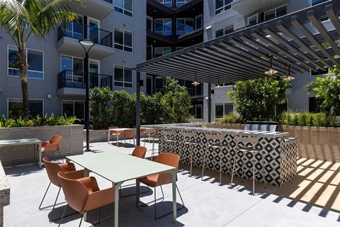 a patio with tables and chairs in front of an apartment building