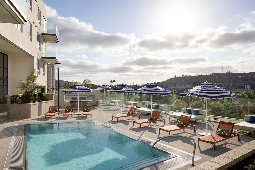 a swimming pool with chaise lounge chairs and umbrellas
