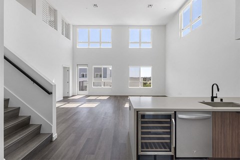 a kitchen and living room with white walls and hardwood floors