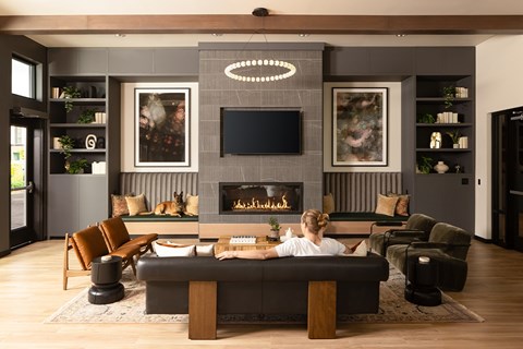 A woman is sitting on a couch in a modern living room with a fireplace.