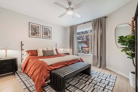 A bedroom with a bed, nightstand, and a window with curtains.