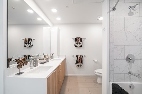 A white bathroom with a marble tile shower.
