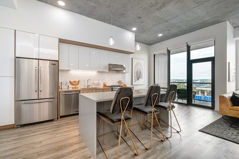 A modern kitchen with a large island and chairs.