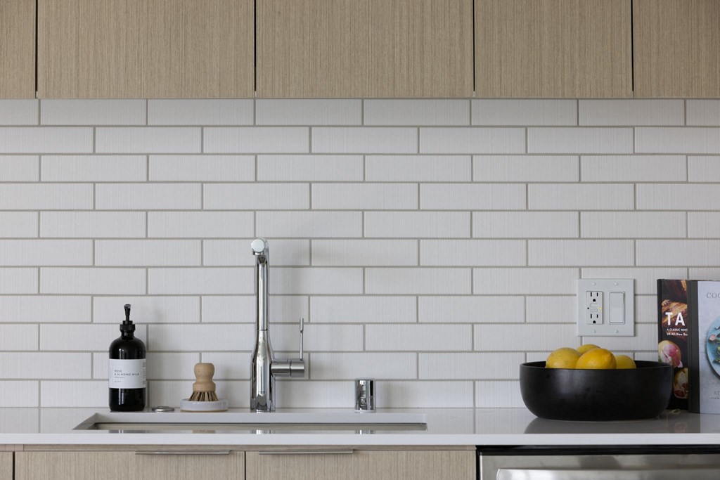 a white kitchen with a sink and a bowl of fruit