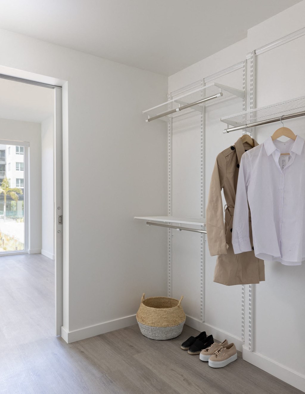 a closet with white clothes and shoes and a basket on the floor