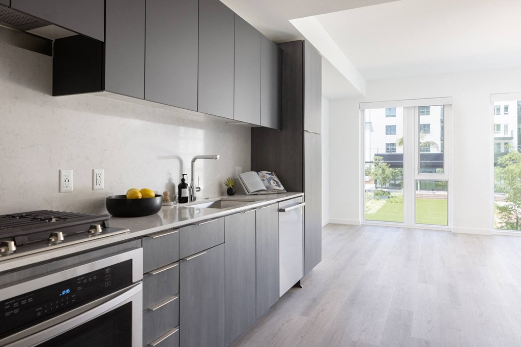 a kitchen with gray cabinets and a stove and a window