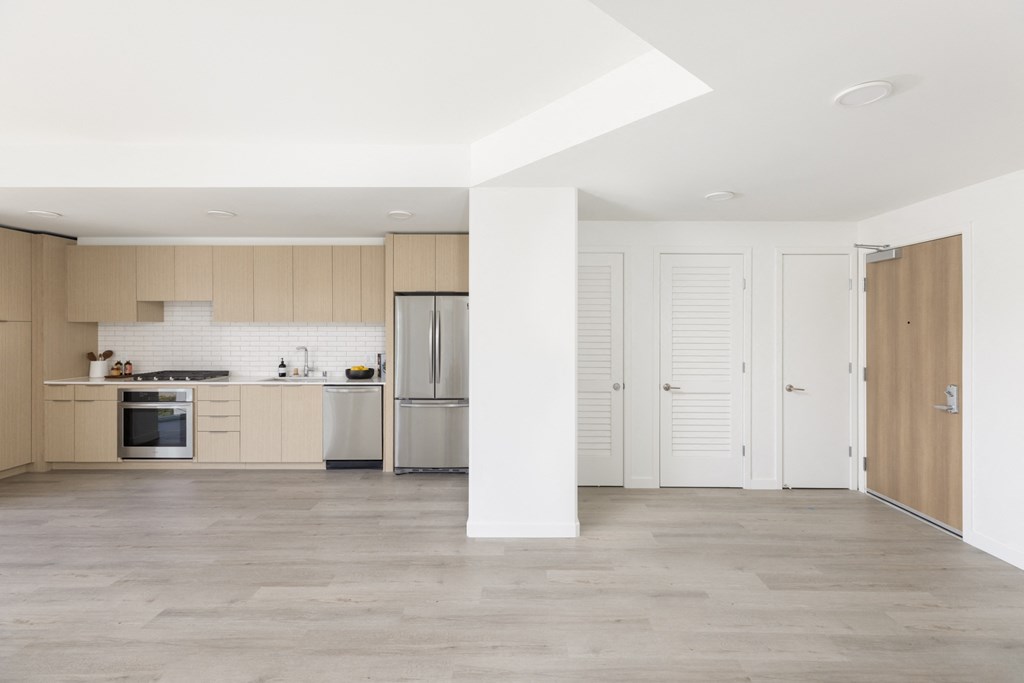 a white kitchen with wooden cabinets and a stainless steel refrigerator