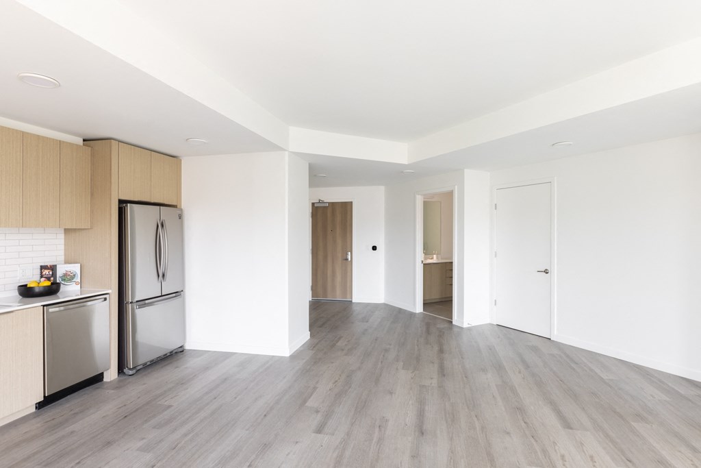 a kitchen and living room with white walls and wood floors
