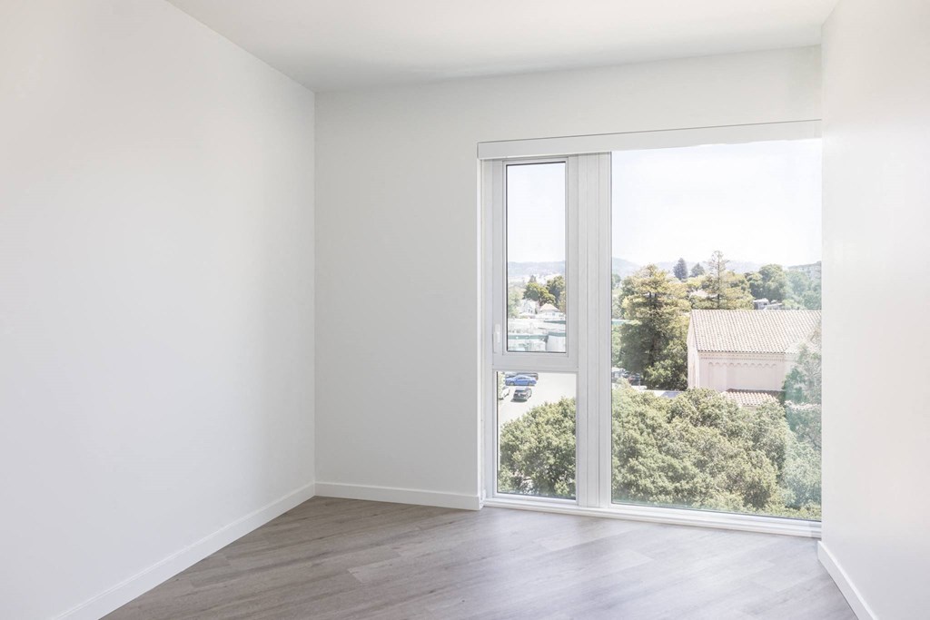 a living room with a large window and wooden floors