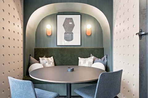 A modern dining room with a round table and grey chairs.