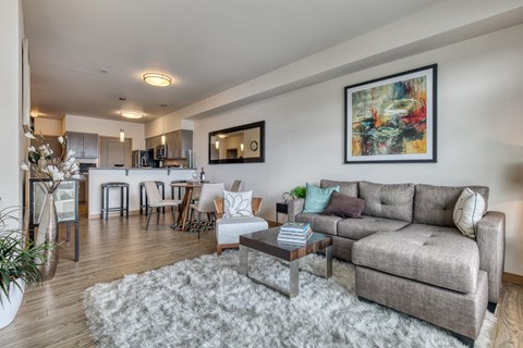 A living room with a grey couch, a coffee table, and a painting on the wall.
