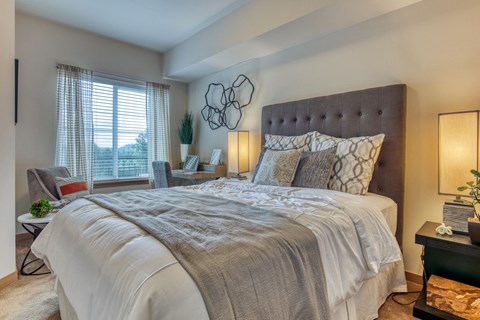 A bedroom with a large bed and a window with curtains.