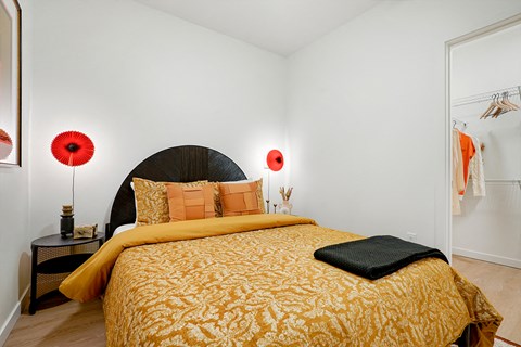 A bedroom with a large bed and two red lamps.