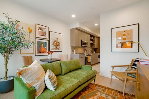A living room with a green couch and a tree.