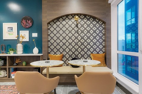 A dining room with a patterned wallpaper and a round table with four chairs.
