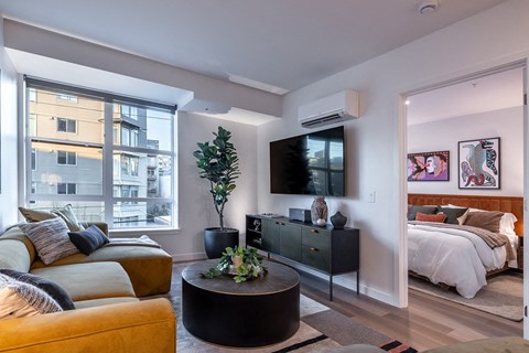 A living room with a yellow couch and a black coffee table.