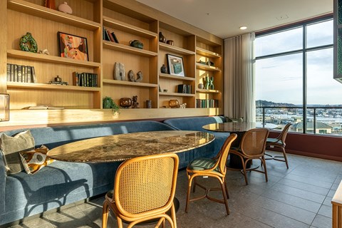A dining area with a table surrounded by chairs and shelves with decorative items.