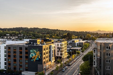 A city street with buildings on either side and cars parked on the side of the road.