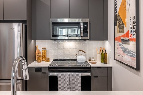 A modern kitchen with a stainless steel refrigerator and a black stove top oven.