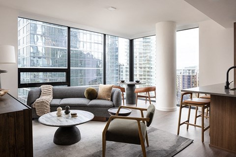 A modern living room with a grey sofa and a large window.