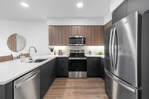 A modern kitchen with a stainless steel refrigerator and wooden cabinets.