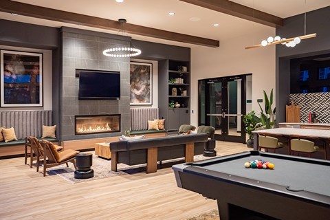 A billiard table is in the middle of a room with a fireplace and a TV.
