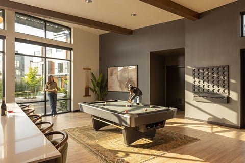 A man is playing pool in a room with a pool table.