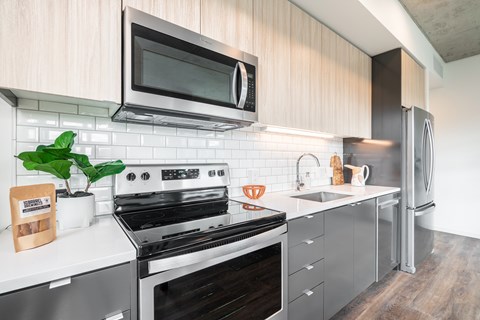 A modern kitchen with a stove, microwave, and refrigerator.
