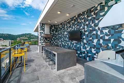A patio with a bar and chairs overlooking a body of water.