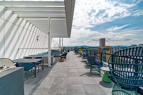 A rooftop patio with blue chairs and tables.