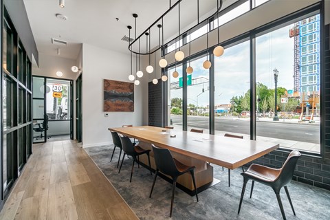 A conference room with a long table and chairs, a wooden floor, and a view of the city outside the windows.