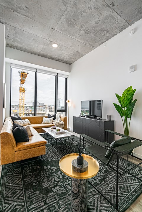 A living room with a brown couch and a glass coffee table.