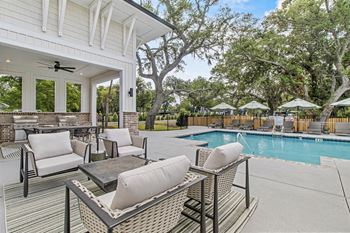 A patio with a table and chairs overlooking a pool.