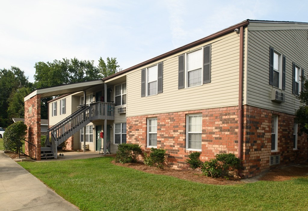 an exterior view of a building with a staircase and a lawn