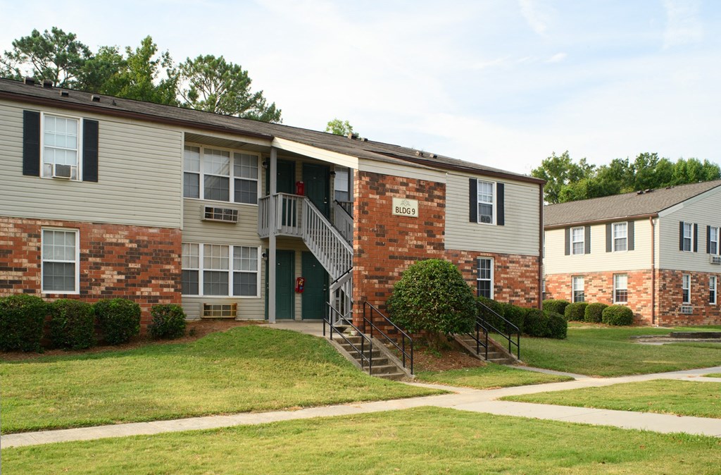 an exterior view of an apartment building with a lawn and sidewalk