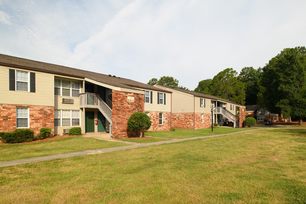 a row of apartment buildings with grass and trees